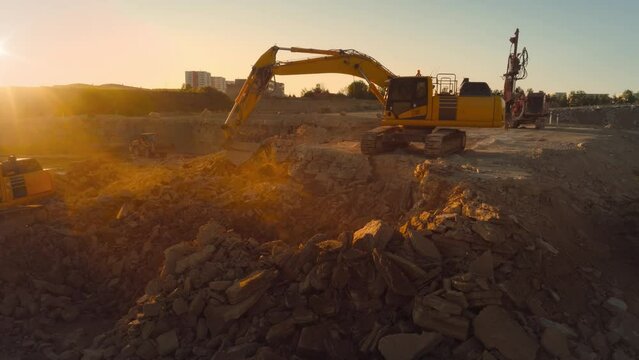 Aerial Drone Shot Of Construction Site On Sunny Day: Industrial Excavators Digging Rocks To Lay Foundation For A New Apartment Building. People Using Heavy Machinery To Complete A Real Estate Project.