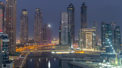 Fototapeta na wymiar Cityscape with skyscrapers of Dubai Business Bay and water canal aerial night to day timelapse.
