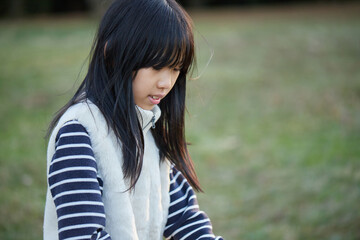 Fototapeta premium 夕方の冬の公園で遊んでいる小学生の女の子の様子