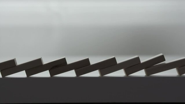 falling line of wooden domino blocks each knocking the next over, domino effect slow motion
