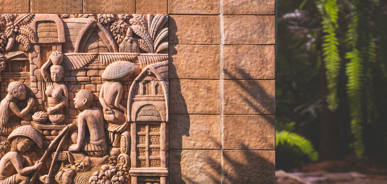 Sunlight on surface of vintage carving clay tile decoration on stone wall in front of home garden in panoramic view