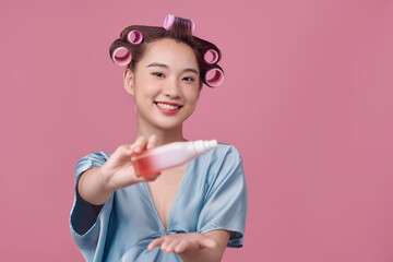 Beautiful young woman holding a bottle in her hand with curlers on her hair