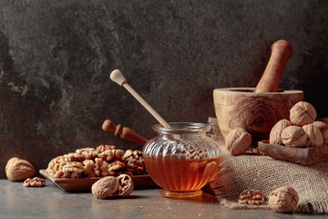 Honey and walnuts on a kitchen table. - obrazy, fototapety, plakaty