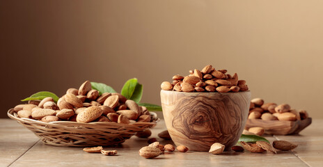 Almond nuts in wooden dishes on a ceramic table.