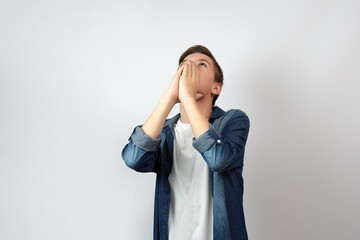 Portrait of praying boy, holding palms on his face.