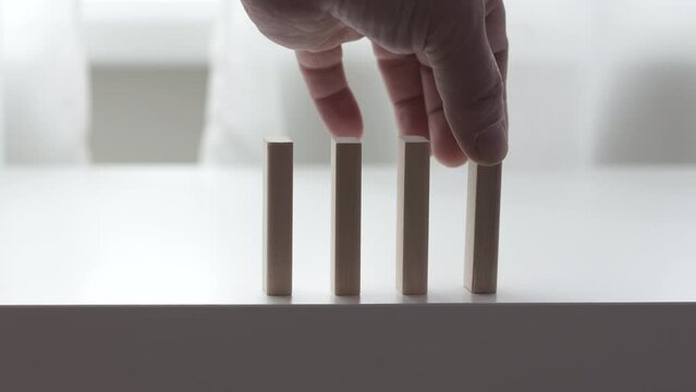 male hand puts wooden domino blocks in a line, domino effect slow motion
