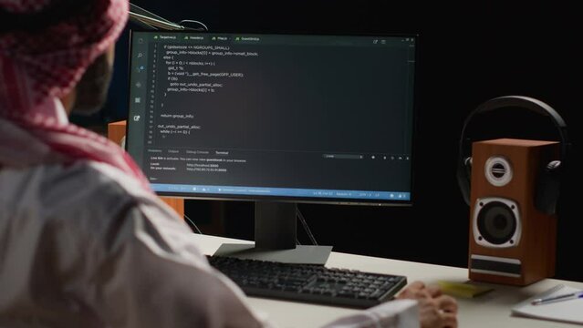 Certified arab engineer writing code on computer screen while in office using Java programming languages. Middle Eastern developer working on fixing database errors while working from apartment office