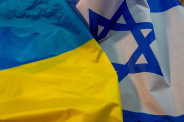 Flags of Israel and Ukraine, made of textile and arranged on a flat surface. Crisis concept