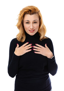 Portrait of surprised forty year old woman asking For Me, isolated on white background. Woman in black turtleneck questioning face putting palms to chest while getting gift and posing in studio.