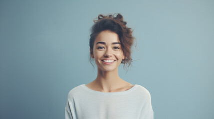 Joyful woman with a messy bun, wearing a light sweater, against a blue background.