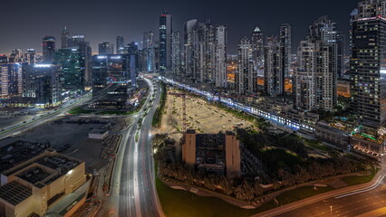 Naklejka na ściany i meble Panorama showing Bay Avenue with modern towers residential development in Business Bay aerial night timelapse, Dubai