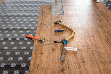 Hammer, ruler with angle bar, tape meter and other tool on laminate vinyl floor