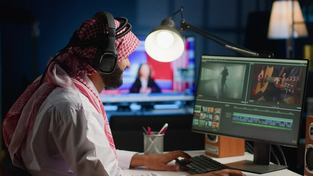Muslim cinematographer wearing headphones while editing project, creating film montage, working with images and sounds. Man using video cutting software to process movie on PC workstation