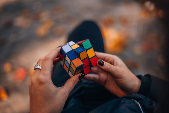 Cubing Challenge: A close-up shot shows a person's hands meticulously manipulating a vibrant Rubik's Cube, fingers gracefully twisting and turning the puzzle's colorful facets. 
