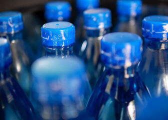 Close-up of Large Number of Packed Blue Bottled Drinking Water with Blue Caps.drinking water bottle background