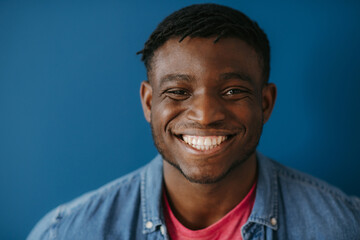 Portrait of handsome young African man in casual wear smiling at camera while standing 