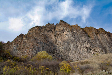 Steep cliffs and golden trees. Autumn landscape and blue sky