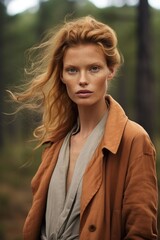 Fototapeta premium Solemn redhead woman captured in a moody forest setting with thoughtful, subtle lighting