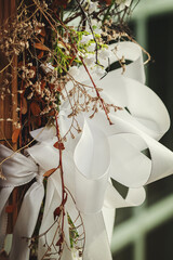 Dekoration mit einer weißen Schleife und trockenen Pflanzen.