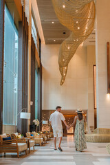 a couple of men and a woman walking in a hotel lobby of a luxury hotel in Thailand - obrazy, fototapety, plakaty