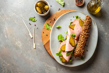 Long sandwich in brown bread with ham and pickled cucumbers. Delicious breakfast or snack, top...