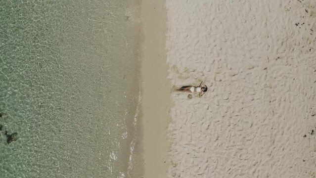 Aerial view of a woman relaxing on Pomponette Public beach along the shoreline, Chemin Grenier, Savanne District, Mauritius.