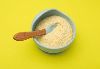 Baby porridge in a plate on a yellow background. Rice porridge for baby's growth and development. Strengthening immunity and health, hypoallergenic