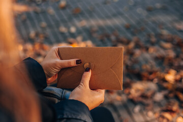 Woman hand holding a brown envelope. Empty earth tones envelope mock up around Colorful falling...