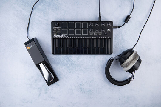piano style Sustain Pedal M-Audio SP-2 brand lie next to the AKAI MPK mini mk2 midi keyboard, on a light background and Closed-back headphones of the beyerdynamic dt 770