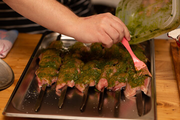 The chef greases the prepared fish fillet with green sauce