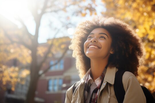 A cheerful high school student with a bright smile stands confidently in a vibrant autumn landscape wearing beige jacket. The image showcases joy and the energetic spirit of youth