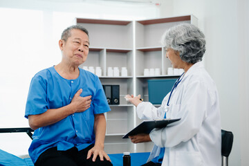 Asian doctor in white suit take notes while discussing and Asian elderly, man patient who lying on bed with receiving saline solution