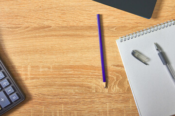 an open notepad for notes, a fountain pen, a pencil calculator and a laptop on a wooden table with a copy space top view