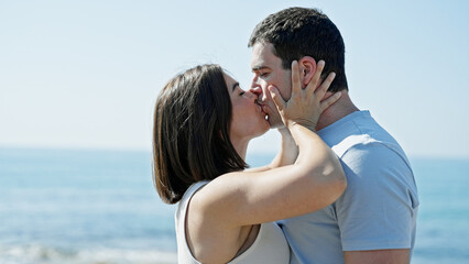 Beautiful couple standing together kissing at seaside
