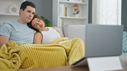 Beautiful couple watching movie on laptop eating popcorn at home