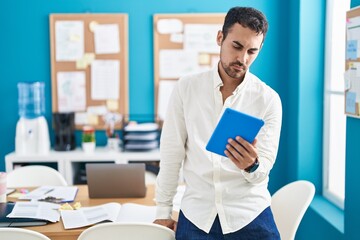 Young hispanic man business worker using touchpad at office