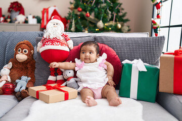 African american baby smiling confident sitting on sofa by christmas tree at home