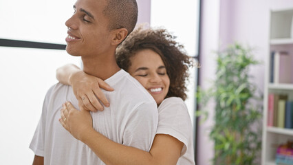 Obraz premium Confident, beautiful couple hugging and smiling in their cozy home, embracing their love and happiness together