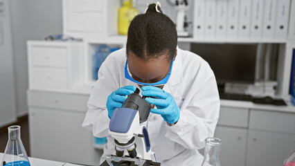 Focused african american woman scientist engrossed in scientific research, on microscope analysis...