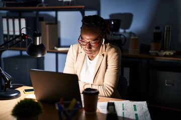 Beautiful black woman working at the office at night with hand on stomach because nausea, painful...