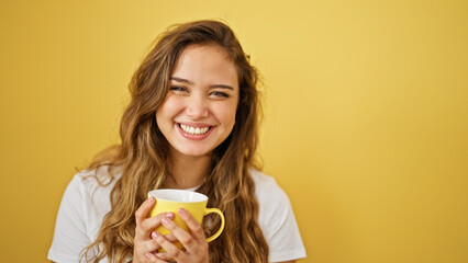 Young beautiful hispanic woman drinking coffee standing over isolated yellow background