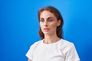 Young beautiful hispanic woman standing with serious expression over isolated blue background