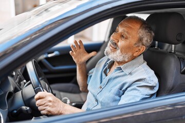 Senior grey-haired man stressed driving car at street