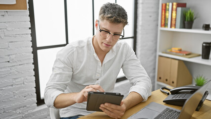 Focused young caucasian business worker intently mastering work on touchpad at the office, exuding...
