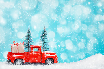 Small Christmas trees and a toy pickup truck with a gift box, snowfall, bokeh light, New Year and Christmas celebration, boxing day.