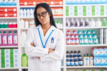 Hispanic woman working at pharmacy drugstore skeptic and nervous, disapproving expression on face...