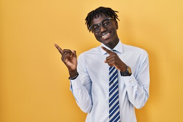 African man with dreadlocks standing over yellow background smiling and looking at the camera...