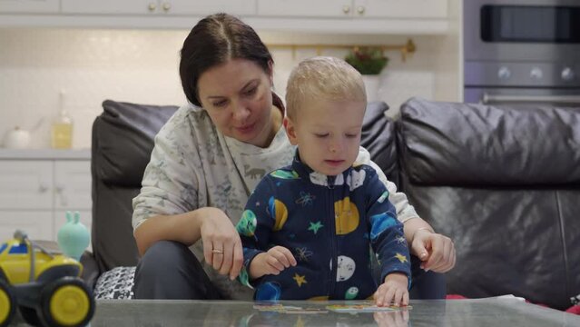 mother and toddler child little boy solving a jigsaw puzzle for kids at home