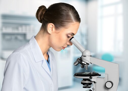 Young scientist looking in a microscope at the laboratory, AI generated image