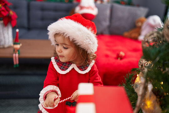 Adorable blonde toddler smiling confident decorating christmas tree at home